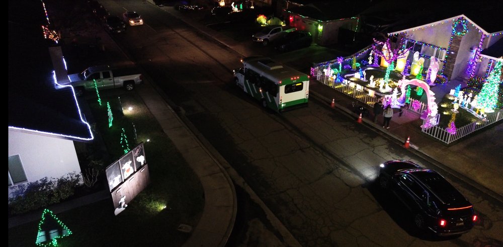 Aerial view of a decorated holiday light display with a tour trolley driving past on the street